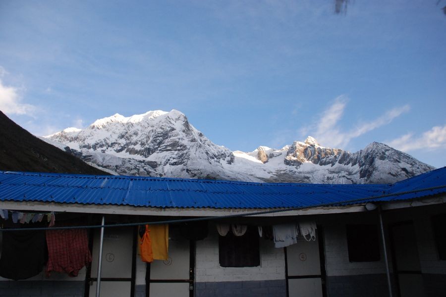 Snow-capped Manaslu peaks behind blue-roofed teahouse with laundry drying